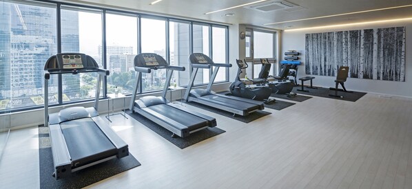 A gym with treadmills, ellipticals, and a rowing machine, large windows with a city view, and a modern interior design. - Grand City Hotel Changwon (Changwon)