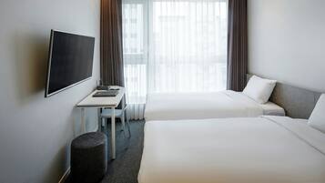 A hotel room with two beds, a TV, a desk, and a chair.