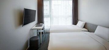 Una habitación de hotel con dos camas, televisión, escritorio y una silla.