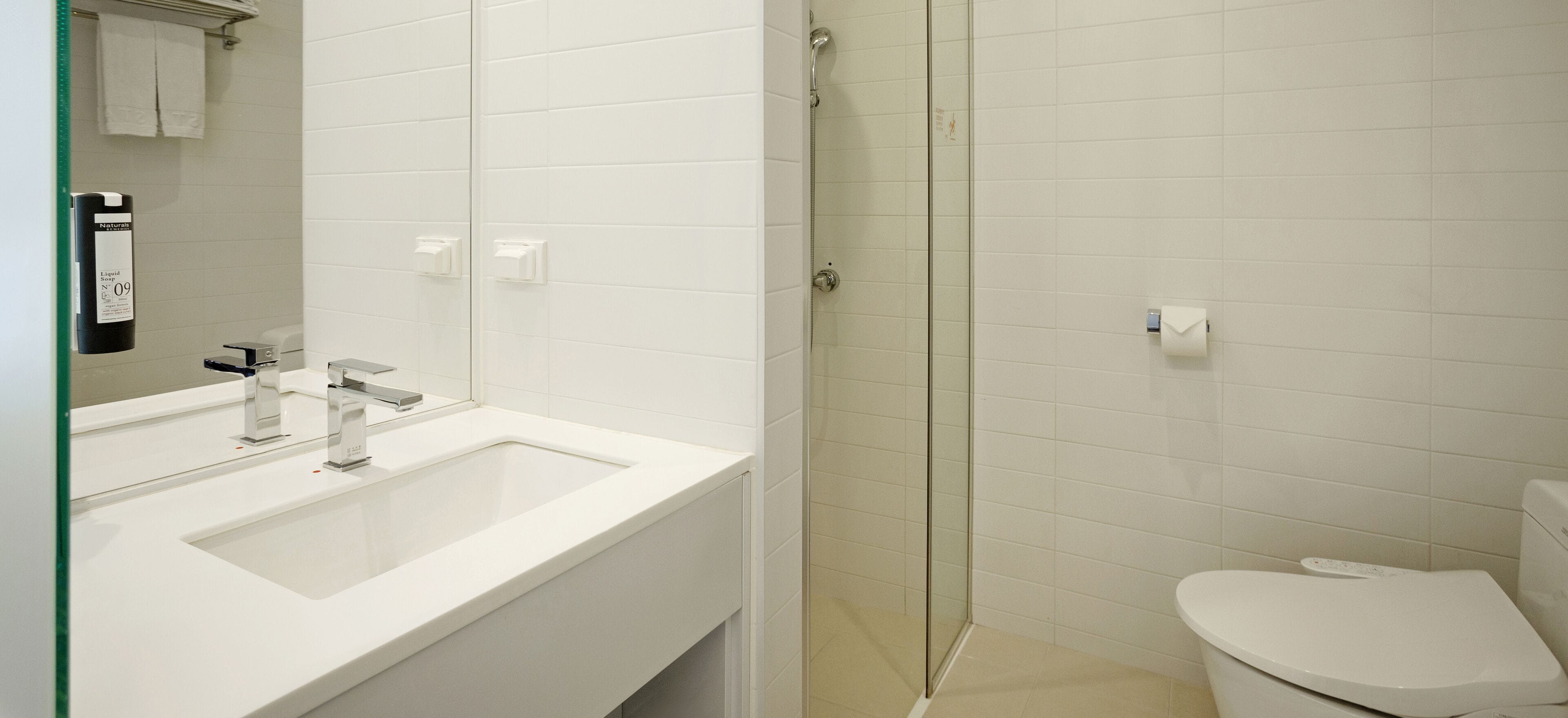 Une salle de bain moderne avec un lavabo blanc, un miroir et des toilettes.