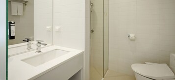 Une salle de bain moderne avec un lavabo blanc, un miroir et des toilettes.