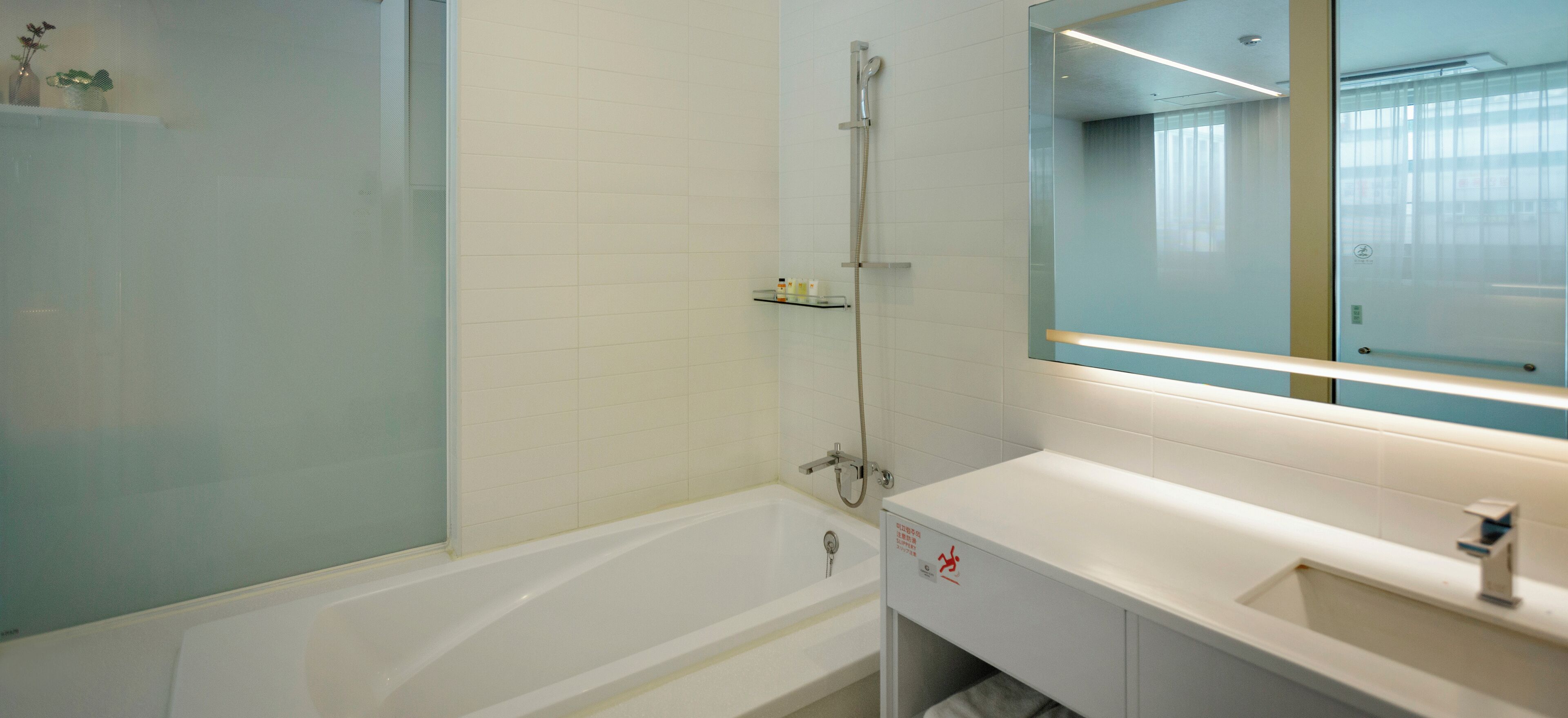A modern bathroom with a bathtub, a shower, and a large mirror.