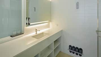 A modern bathroom with a large mirror, a sink, and a shower area.