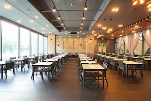 Un restaurante espacioso con techos altos, iluminación moderna y grandes ventanales.