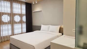 A hotel room with a bed, a bedside table, and a window with curtains.