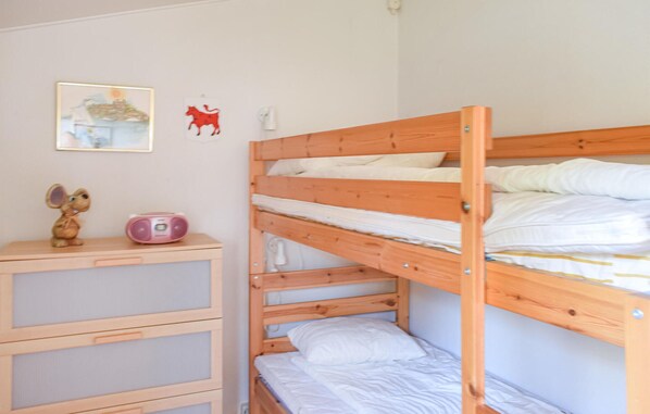 Une chambre avec un lit superposé, un bureau et une chaise, une radio et une petite figurine d’animal.