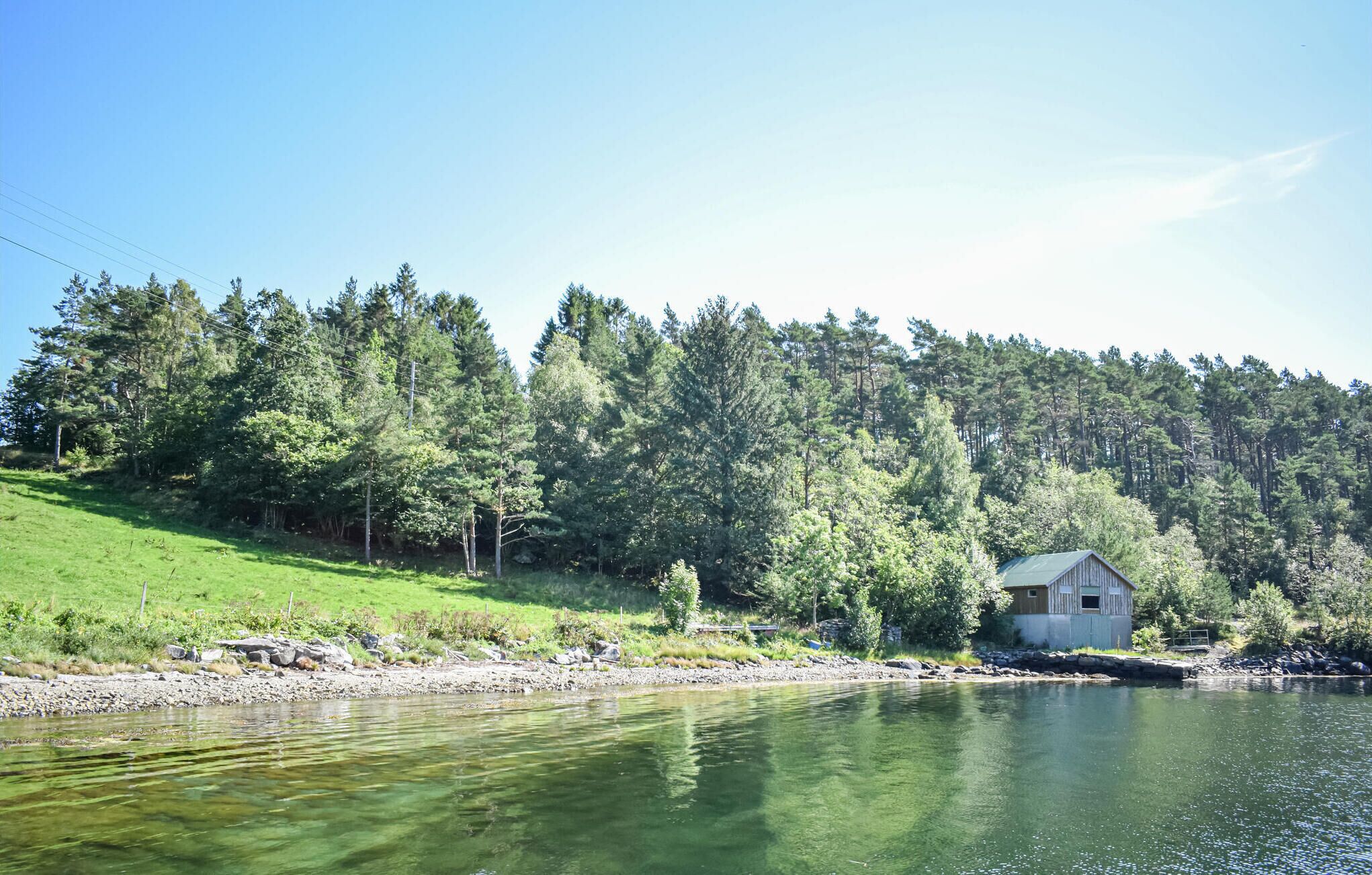 Pieni mökki kirkkaan järven rannalla, jota ympäröi tiheä metsä.