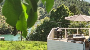 Eine Terrasse mit Sitzgelegenheit und Blick auf einen von Bäumen umgebenen See.