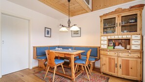 A dining area with a wooden table, blue upholstered bench, and chairs. A wooden cabinet with glass doors and labels is to the right. - Kellerstoeckl in Strem (Strem)