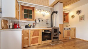 A kitchen with wooden cabinets, a built-in oven, a sink, and a stove. - Kellerstoeckl in Strem (Strem)