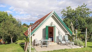A small, single-story house with a sloped roof, a green door, and a patio with outdoor furniture. - Kellerstoeckl in Strem (Strem)
