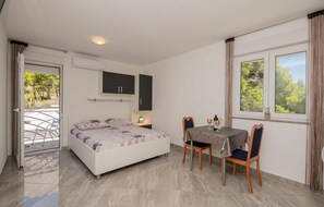 Relax in this serene bedroom with a large bed and a view of lush greenery outside, featuring a small table and chairs.