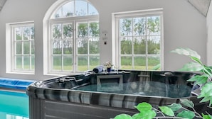 Ein Whirlpool in einem Raum mit großen Fenstern und Blick ins Freie.