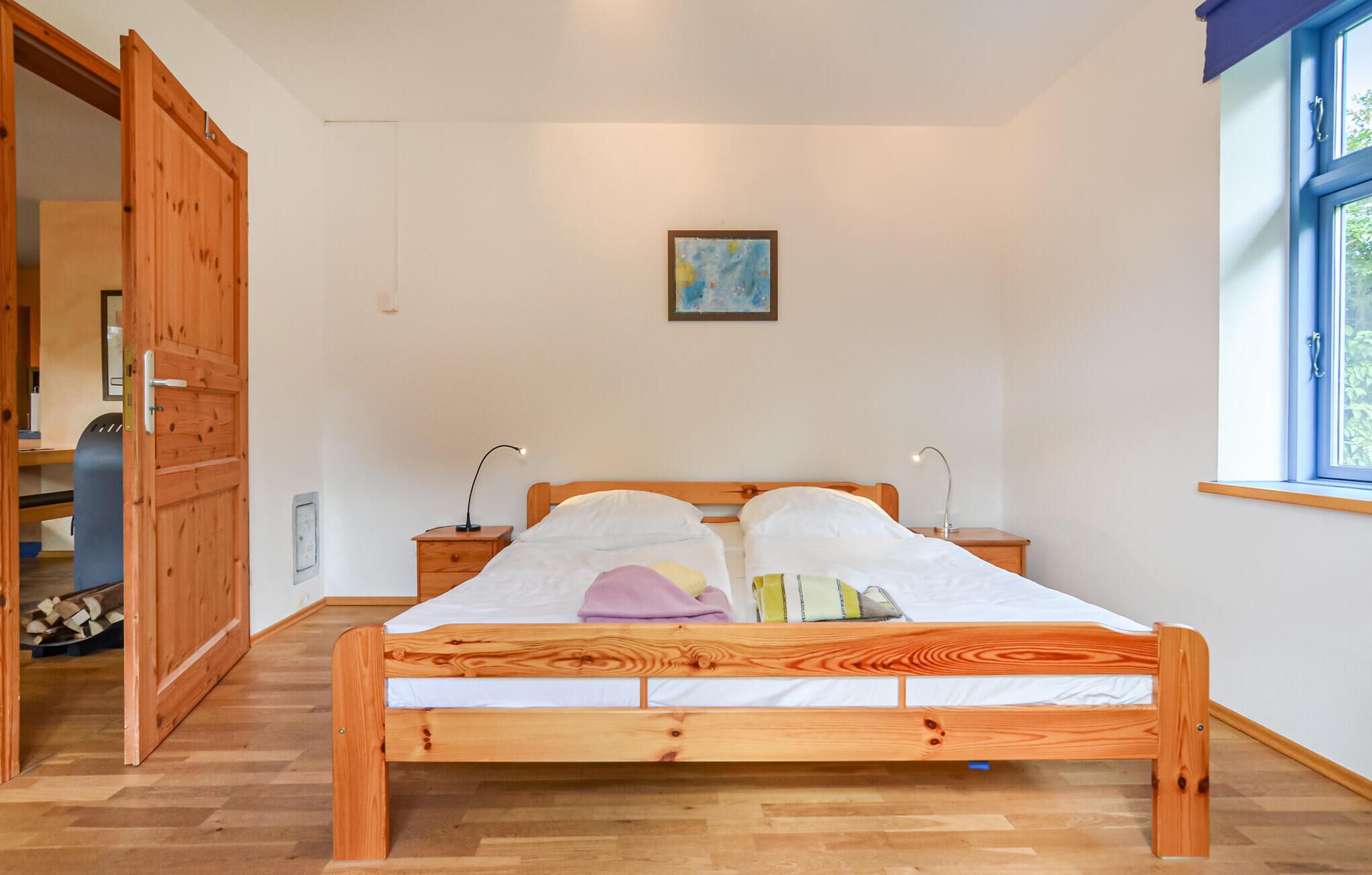 A wooden bed in a room with a window and a door.