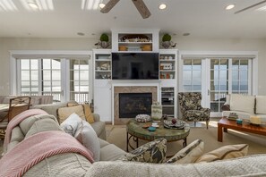A spacious living room with a fireplace, a television, and a large window.