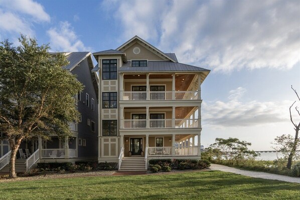 Ein zweistöckiges Haus mit Balkon, Veranda und Blick auf das Wasser.