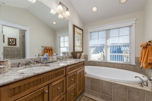 A bathroom with a double sink vanity, a large mirror, a bathtub, and a window with blinds. - Sunset Island 8 Beach Side Mews (Ocean City)