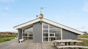 A modern building with large windows and a wooden deck. - Cozy home in Harboøre with sauna (Harboøre)
