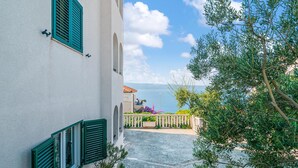 Un sendero estrecho que lleva a un edificio con contraventanas verdes y vistas al mar.