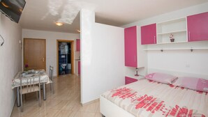 Une chambre à coucher avec un lit, un bureau et une chaise. On peut apercevoir une salle de bain à travers une porte ouverte.