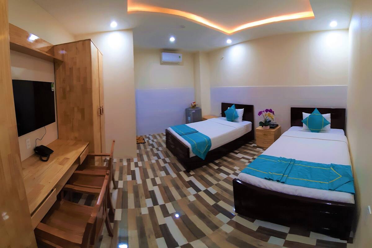 A hotel room with two beds, a TV, a desk, and a wardrobe.