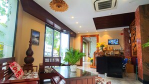 A spacious lobby with a reception desk, seating area, and large windows allowing natural light.