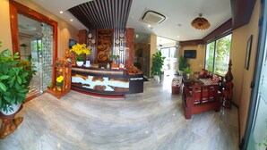 A reception area with a marble floor, a reception desk, and a seating area with a sofa and chairs.