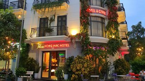 A hotel with a classic architectural style, featuring balconies with railings and potted plants.
