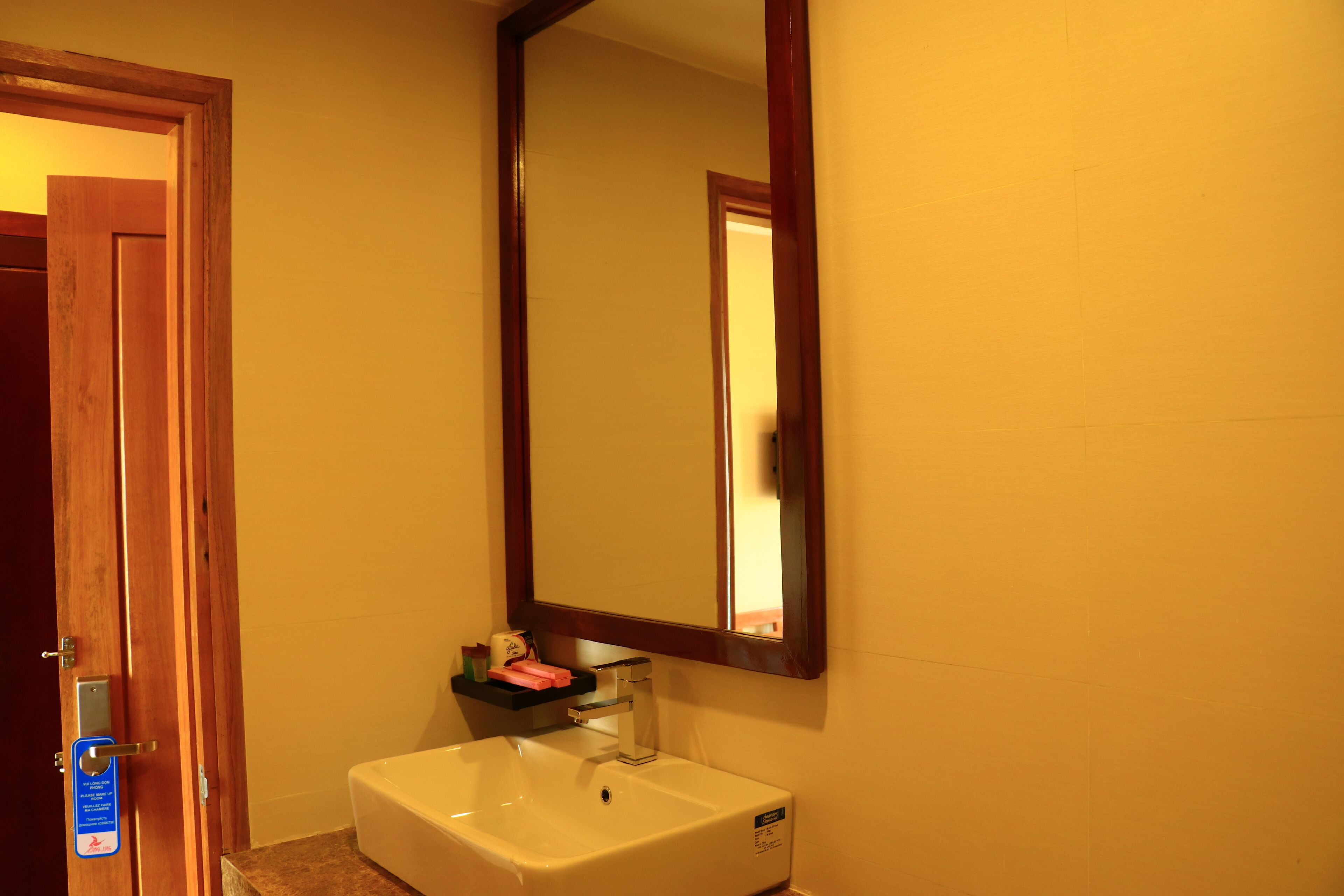 A bathroom with a white sink, a mirror, and a wooden door.