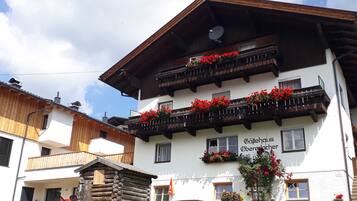 Ein traditionelles alpines Gebäude mit Holzbalkonen, Blockhausbauweise und Blumenkästen.