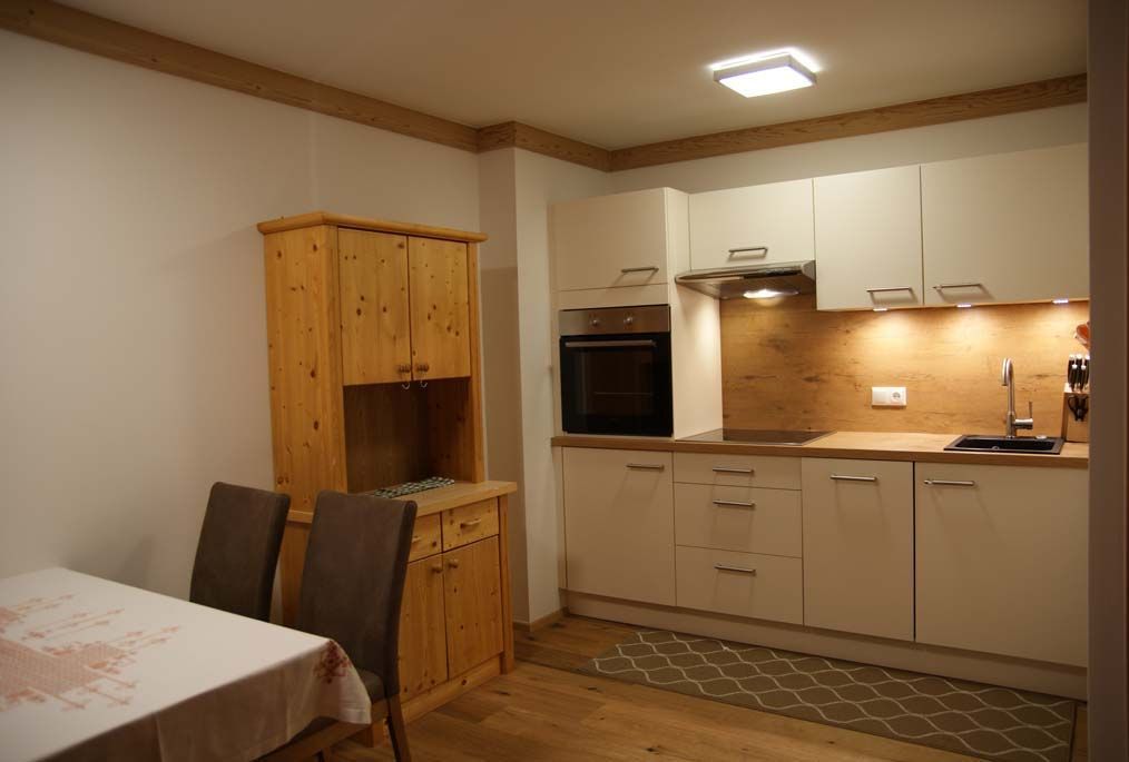 Una cocina compacta con armarios de madera, horno empotrado y comedor con mesa y sillas.