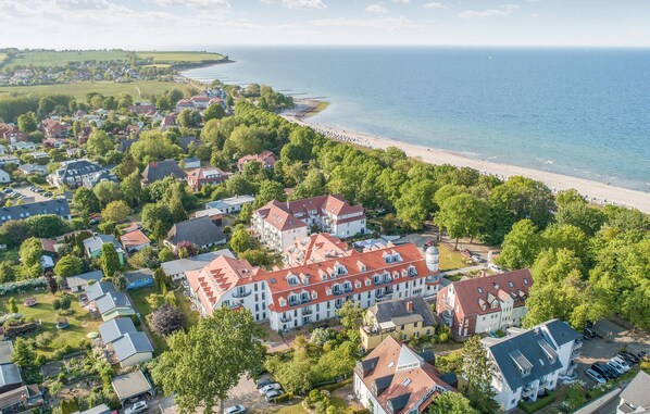 Vista aérea de uma área residencial costeira com casas, uma praia e uma grande extensão de água.