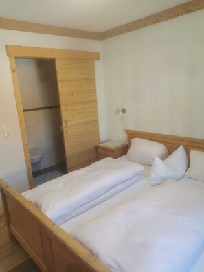 Een slaapkamer met een houten bed, een nachtkastje en een garderobe.