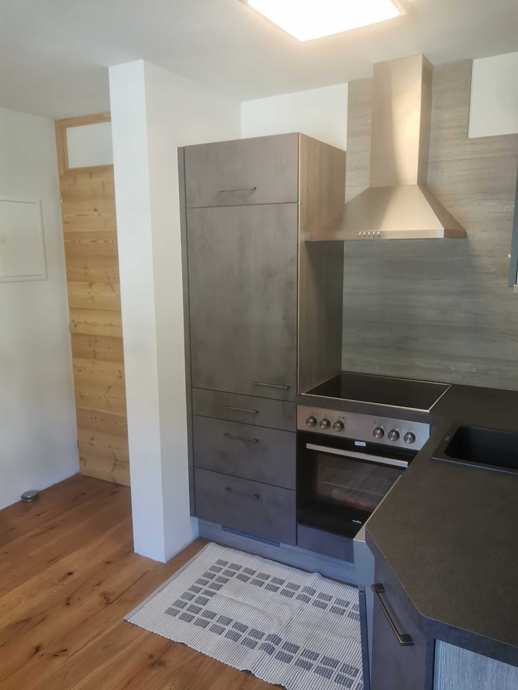 Eine moderne Küche mit Einbauofen, Kochfeld und Holzwand.