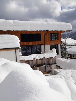 Ein zweistöckiges Gebäude mit Holzfassade und großen Fenstern, umgeben von Schnee.