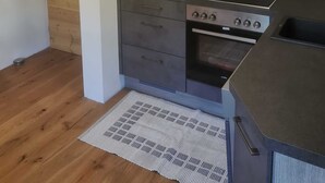 A modern kitchen with a built-in oven, a stovetop, and a wooden wall.