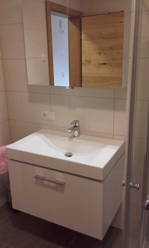 Une salle de bain avec un lavabo blanc, un miroir au-dessus et un meuble en bois.