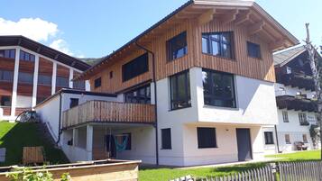 Ein mehrstöckiges Gebäude mit Balkon, großen Fenstern und einer Holzfassade.