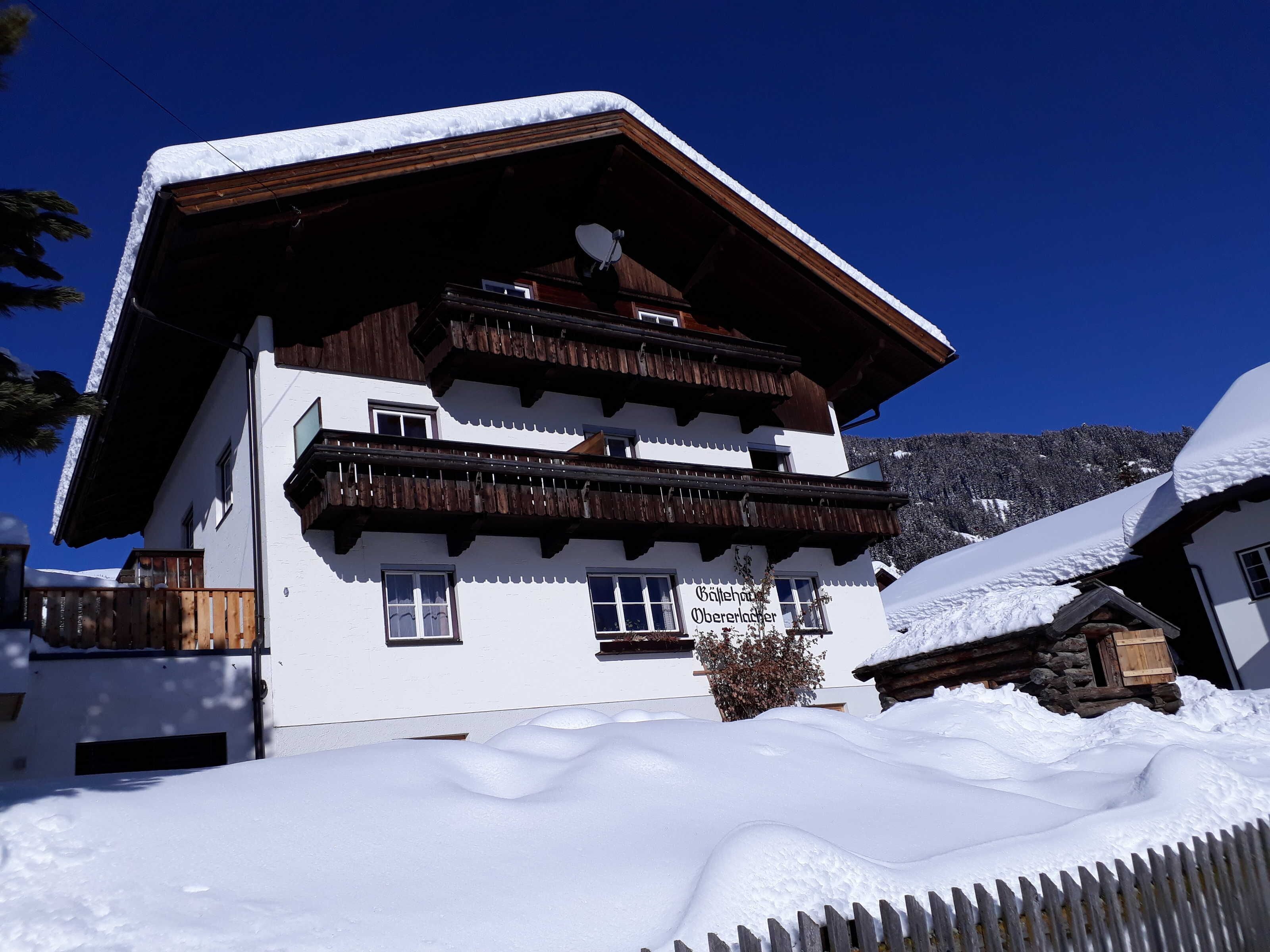 A multi-story building with a snow-covered roof and balconies, surrounded by snow.