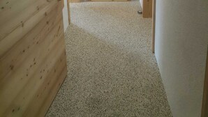 A hallway with wooden doors, carpeted floor, and white walls.