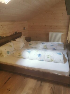 Une chambre dans un chalet en bois, avec un lit, une table de chevet et un radiateur.