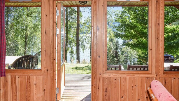 Une cabane en bois dotée d’une grande porte vitrée donnant sur une terrasse.