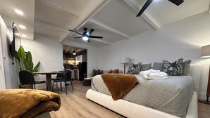Un dormitorio moderno con una cama grande, un escritorio y una zona de comedor.