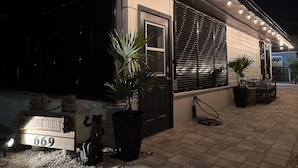 Una casa con un letrero que dice "Beach House 669", una maceta grande e iluminación exterior.