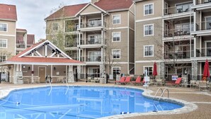 Une piscine entourée d’un immeuble résidentiel à plusieurs étages, doté de balcons et d’espaces de détente en plein air.