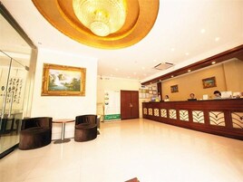 A hotel lobby with a reception desk, seating area, and artwork on the walls.