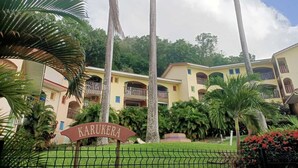 A hotel with multiple buildings, palm trees, and a sign that reads "Karukera".