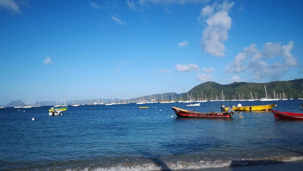 A marina with various boats docked, calm water, and a clear sky.
