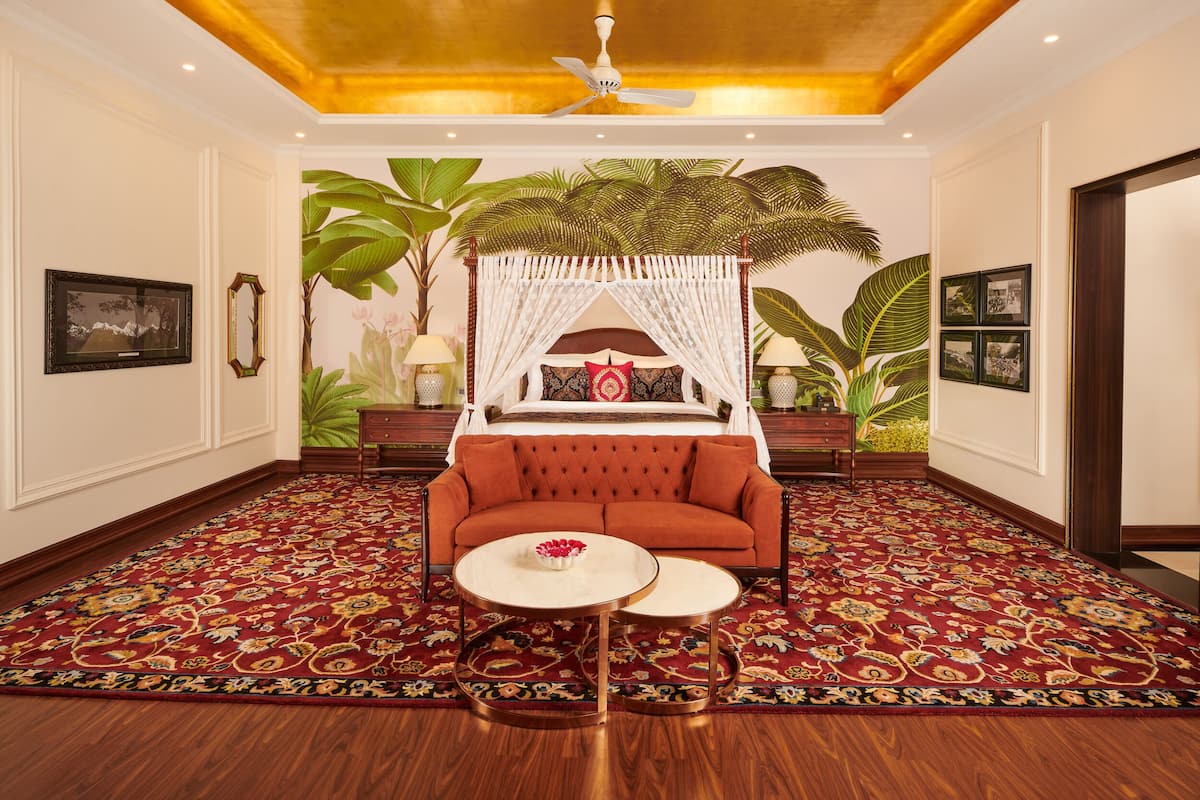 A room with a red sofa, a canopy bed, a round coffee table, and a patterned carpet.