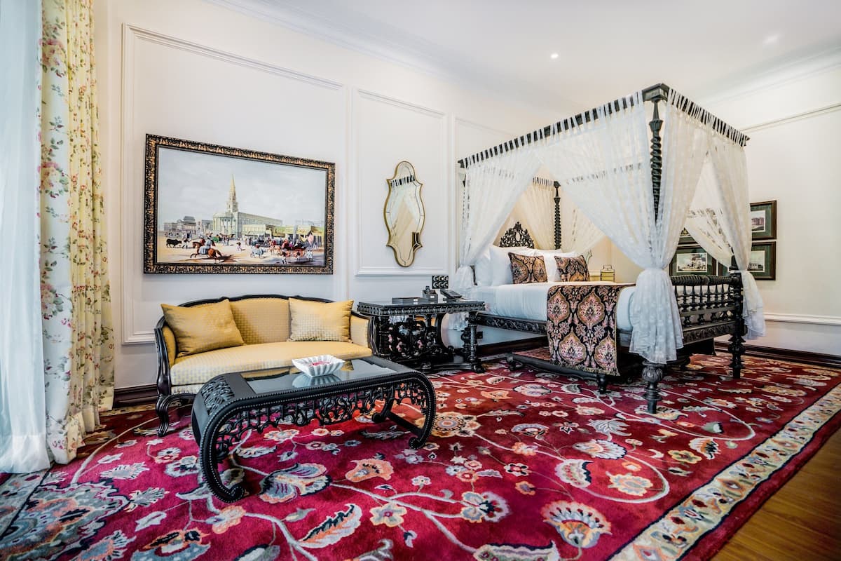 A traditional room with a four-poster bed, a sofa, and a coffee table.